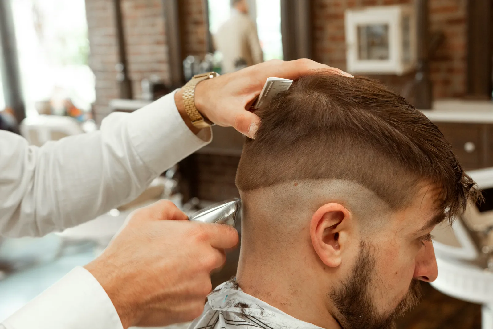 Profissional concentrado no corte de cabelo de um cliente